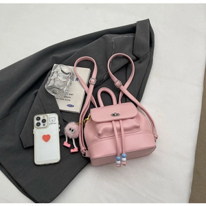 Dettaglio mini zaino in pelle PU rosa con chiusura a rotazione e ciondolo a mostro