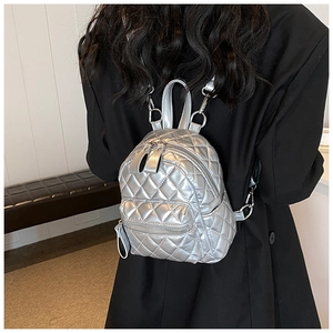 Detail of silver quilted mini backpack with metallic finish and zipper texture
