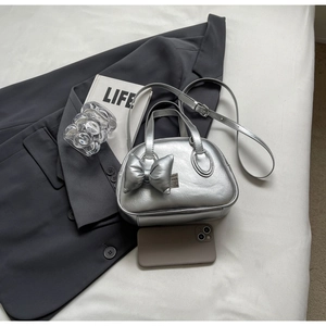 Detailansicht silberne Metallic-Muschel-Tasche mit Schleife auf einem Magazin-Layout