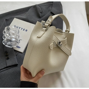 Detail der cremefarbenen Beuteltasche mit Litschi-Textur und Metallverschluss