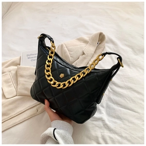 Detail shot of black quilted crescent bag with chunky gold chain and flower hardware