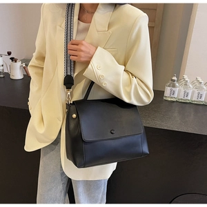 Detailansicht der schwarzen Lederhandtasche mit modischem geometrischem Breitgurt
