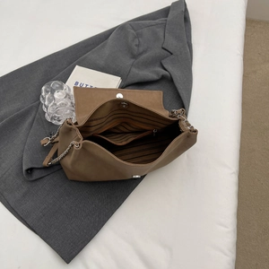 Detailed interior of brown tote bag showing striped lining, zipper pocket and magnetic buckle