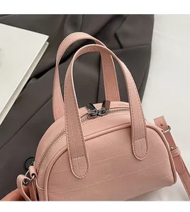 Détail du mini sac à main rose gaufré crocodile avec doubles poignées et fermeture éclair en métal