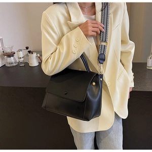 Detailansicht der schwarzen Ledertasche mit stylischem schwarz-weiß gewebtem Schultergurt