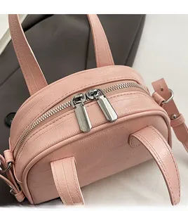 Détail des doubles fermetures éclair argentées et texture crocodile sur le sac en cuir rose