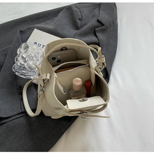 Detailansicht der beigen Eimer-Tasche aus Leder mit Platz für Smartphone und Lippenstift