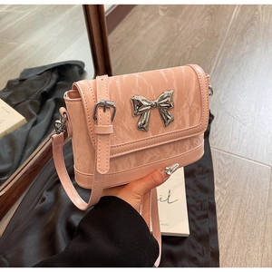 Close-up of pink marbled shoulder bag featuring a decorative silver metal bow clasp