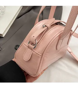 Gros plan sur la texture crocodile rose et les coutures artisanales de ce sac à main