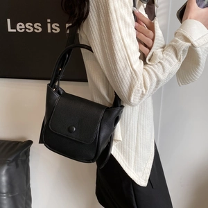 Minimalist black lychee texture leather shoulder bag shown at a 45-degree angle on a model