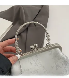 Close-up of vintage silver handbag featuring floral jacquard fabric and metal handle