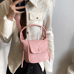 Pink lychee texture crossbody bag with top handle and wide strap on model mirror shot