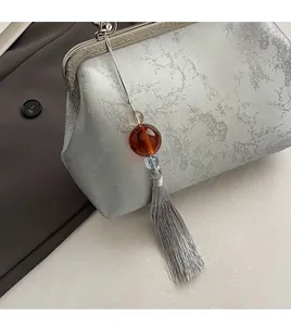 Detail of silver-grey jacquard handbag with mountain pattern and silk tassel charm