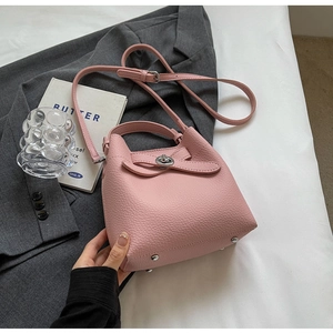 Detailansicht der rosa Eimer-Handtasche aus Litschi-Leder mit Metallfüßen auf der Unterseite