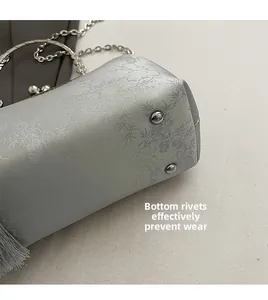 Detail of metal bottom rivets on silver embroidered handbag to prevent surface wear and tear