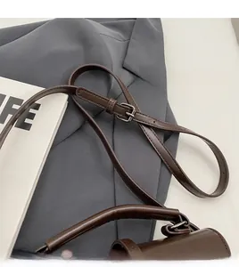 Detail of adjustable slim shoulder strap and top handle on dark brown leather handbag