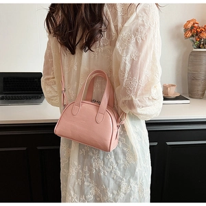 Petit sac à main rose gaufré lézard présenté avec des accessoires de bureau lifestyle