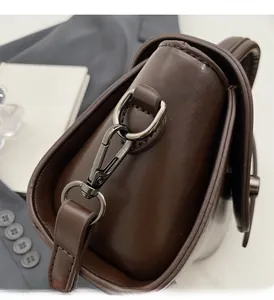 Detail of dark brown polished leather bag featuring premium dark grey metal hardware hooks