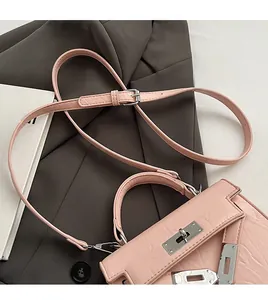 Detail of pink croc-embossed mini bag with silver twist lock and adjustable shoulder strap
