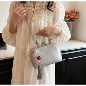 Close-up of a vintage-style jacquard purse with silver floral patterns and amber tassel