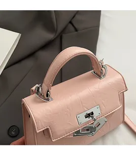 Detail of light pink wrinkled leather handbag with silver rotating lock on a grey blazer