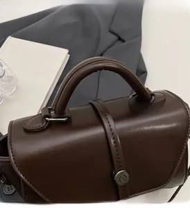 Detail of dark brown leather handbag with sturdy handle and retro metal buckle design