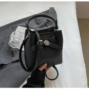 Detail einer schwarzen Eimer-Handtasche aus genarbtem Leder mit silbernem Drehverschluss
