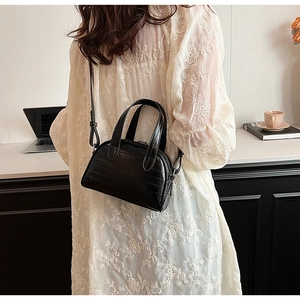 Détail d'un mini sac à main noir élégant avec gaufrage crocodile porté par un mannequin