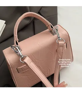 Detail of light pink crossbody bag showing detachable silver metal ring and hooks