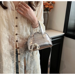 Détail du sac argenté métallisé avec nœud en perles et pendentif en cœur
