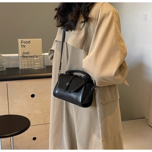 Close-up of a stylish black leather crossbody bag styled with a neutral casual outfit