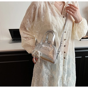 Détail du mini sac argenté texturé avec pendentif à pompon de perles élégant et chic