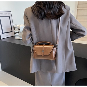 Detail of vintage brown leather handbag with round buckle and adjustable shoulder strap