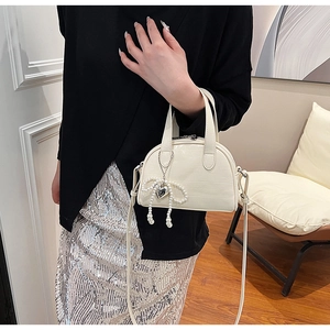 Détail du sac à main blanc à texture crocodile avec nœud en perles sur modèle