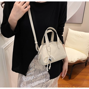 Détail du sac en cuir gaufré blanc crème avec perles et breloques en forme de cœur