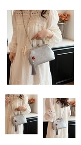 Detail of silver gray embroidered satin bag with vintage metal handle and long tassel