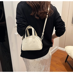Détail d'un sac à main beige gaufré crocodile avec poignées rondes et bandoulière