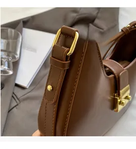 Gros plan détaillé sur le cuir marron et la boucle en métal doré brillant de ce sac à main
