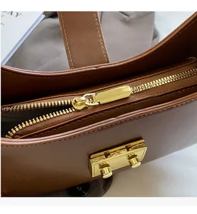 Détail du zip doré et de la boucle métallique sur le sac à bandoulière en cuir marron