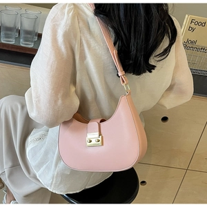 Sac demi-lune rose avec boucle dorée porté comme un sac à bandoulière élégant sous le bras