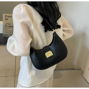 Détail d'un sac hobo noir avec boucle dorée présenté sur une femme en studio