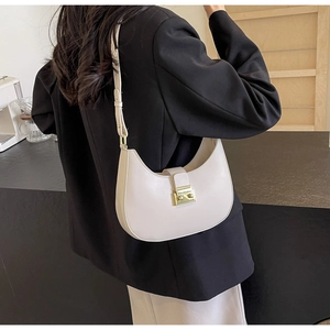 Détail d'un sac selle demi-lune en cuir beige avec bandoulière réglable et boucle d'or