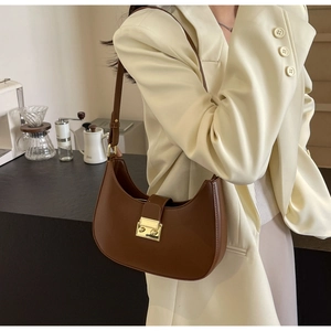 Vue détaillée du sac demi-lune en cuir marron avec boucle dorée sur le mannequin