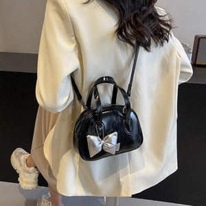 Glänzende schwarze Tasche mit silbernem Schleifenanhänger und verstellbarem Riemen