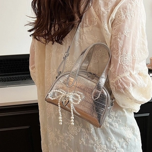 Sac à main argenté effet croco avec nœud en perles et pendentif cœur sur modèle