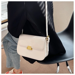 Detail of a creamy white crossbody bag featuring a classic gold square metal clasp on a flap