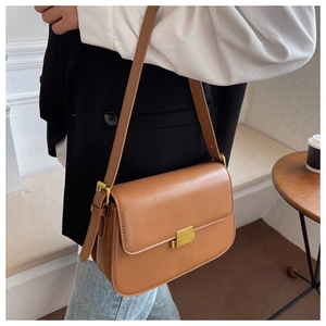 Detail view of a retro caramel leather crossbody bag with a matte gold square metal clasp