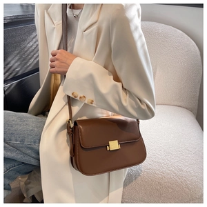 Detailed side view of a brown vintage leather crossbody bag with golden metal buckle on model