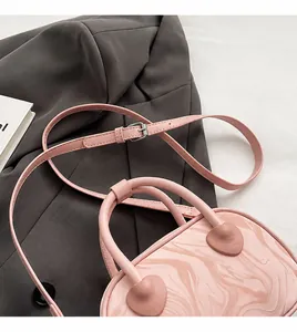 Detail of pink marble textured handbag with adjustable strap and metal buckle on gray blazer