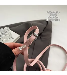 Detail of adjustable thin leather strap with silver metal buckle on a pink handbag